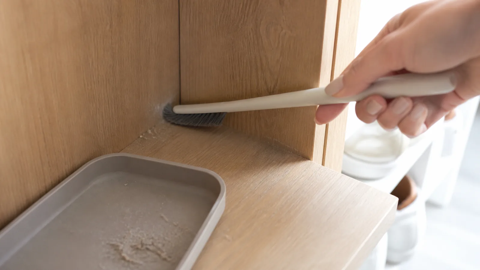 靴箱の奥角を細いブラシで整える手元